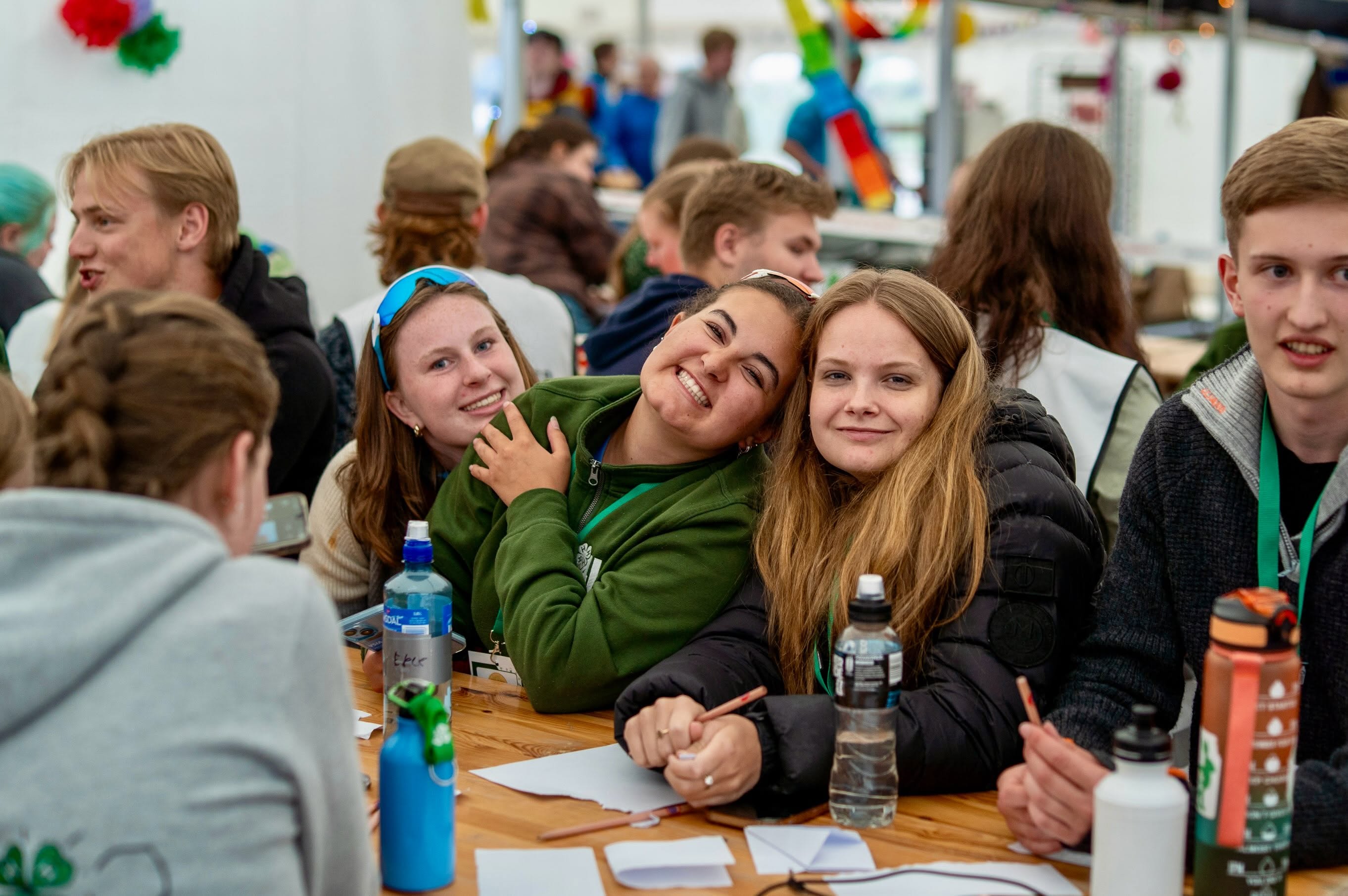 Ungdommer som smiler sammen rundt et bord på leir